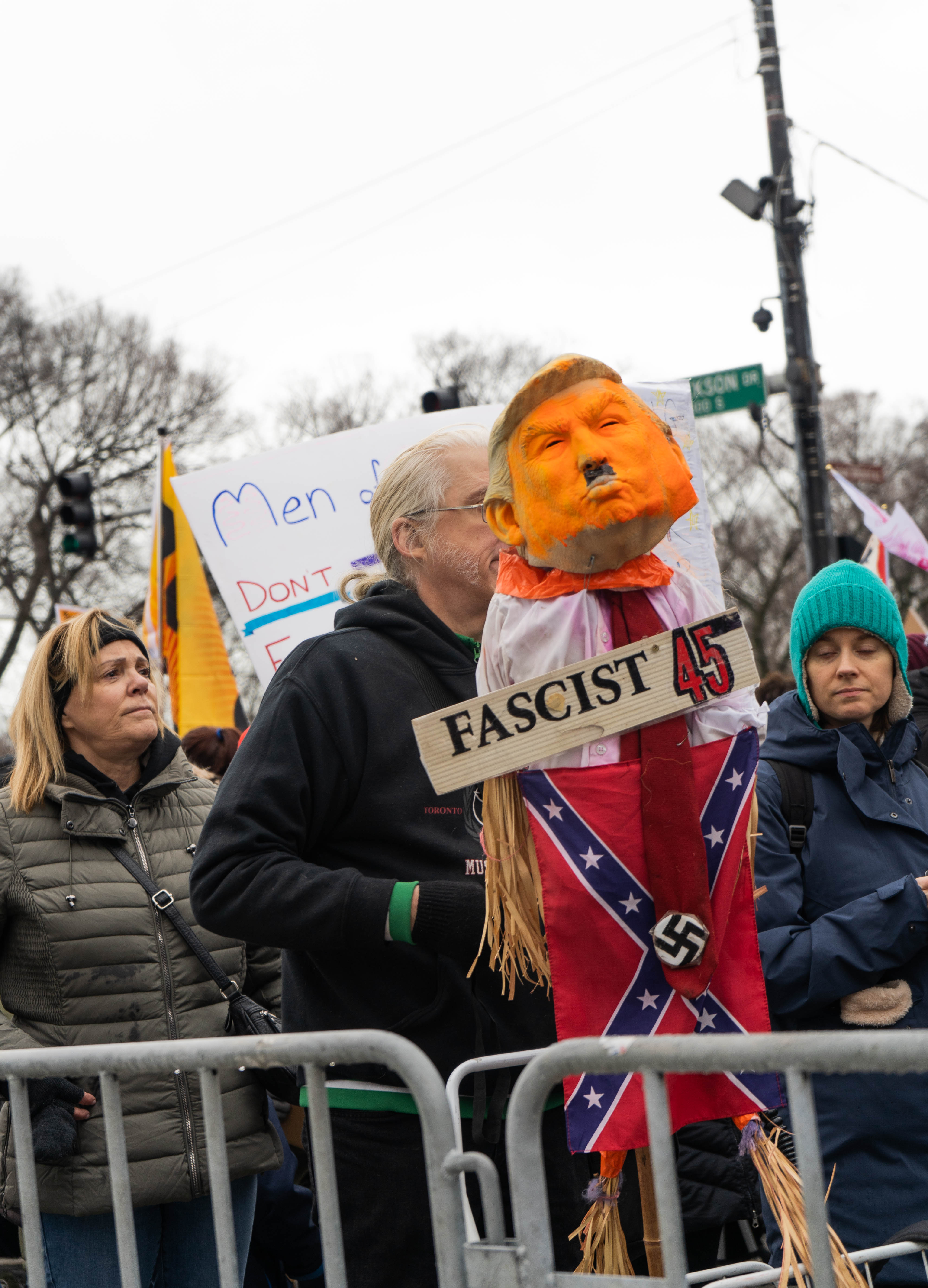 One protester carries a vividly orange mask of Donald Trump over a confederate flag and a sign reading "fascist."
