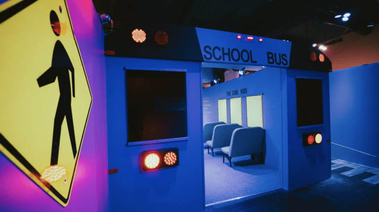 A view at an installation designed to be a blue school bus with a designated "cool kids" section.