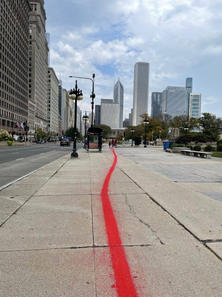 A red line runs along the concrete sidewalk of Michigan Ave. in Chicago.