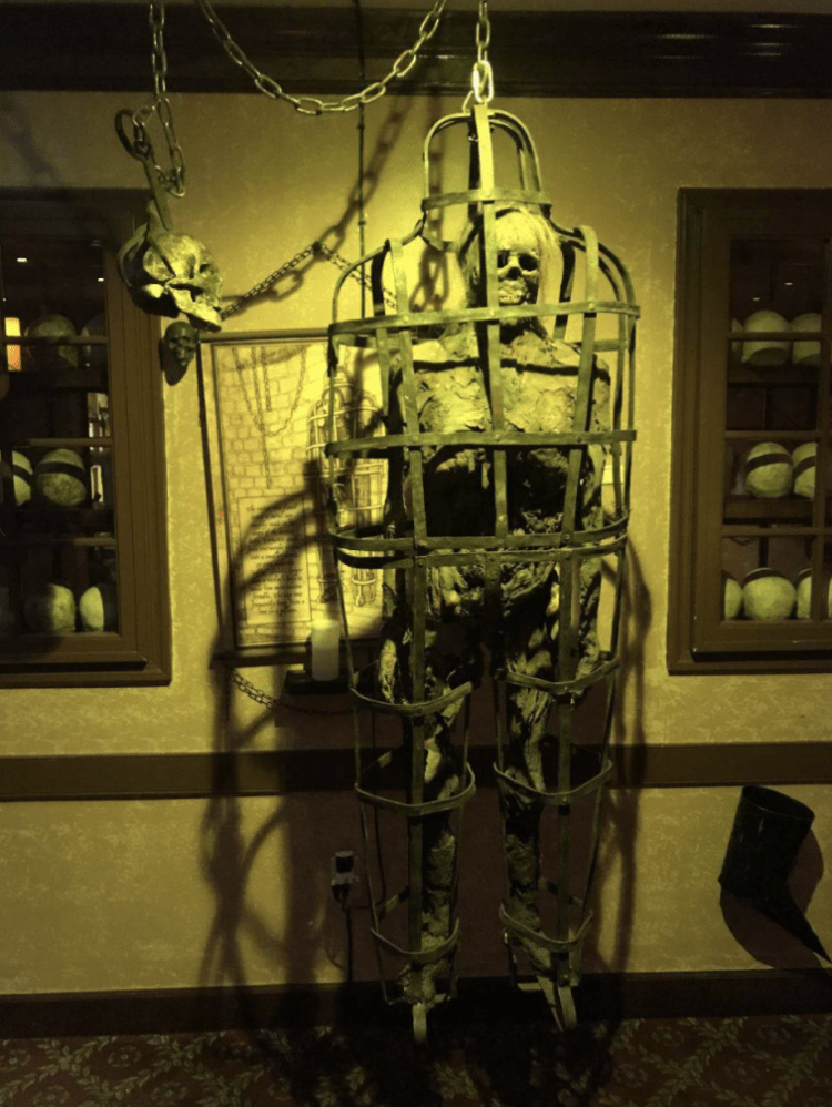 A mannequin skeleton is confined in a large cage.