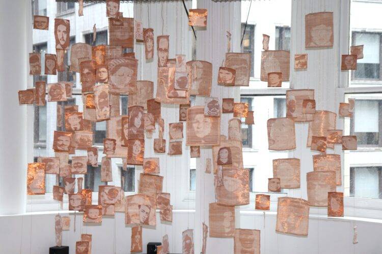 Copper portraits of disappeared Chileans hang in a white gallery space.