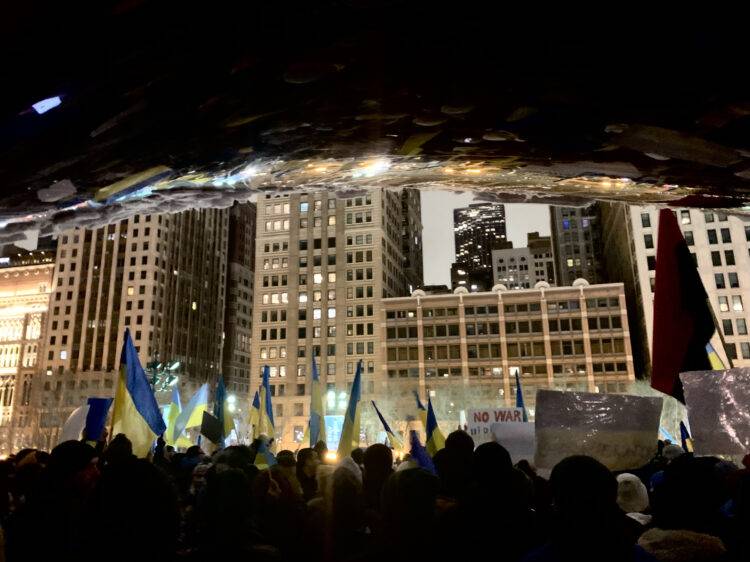 A crowd holding Ukrainian flags gathers in front of Chicago's "Cloudgate."