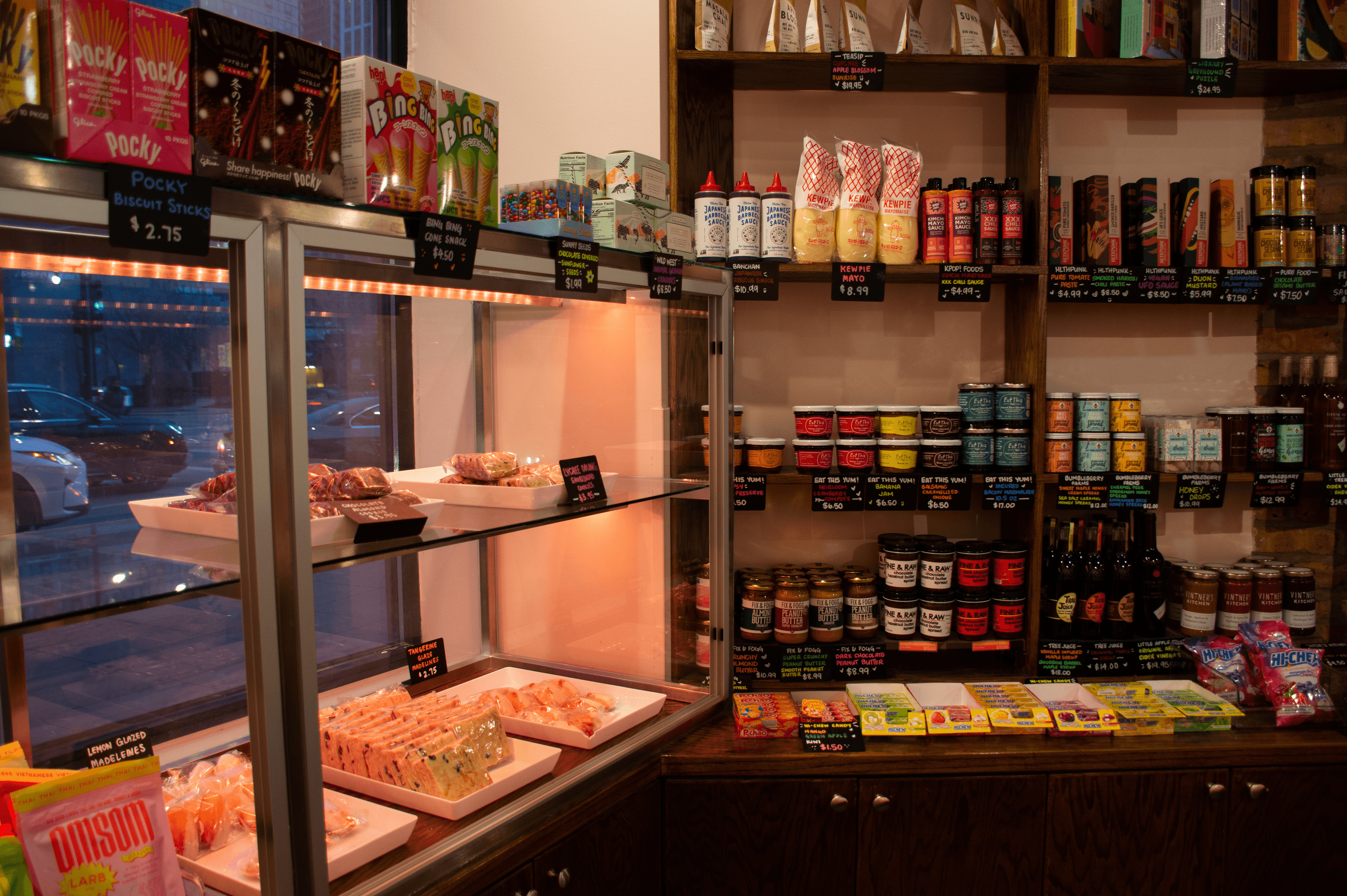 Pastries behind glass and a shelf filled with different snacks and other treats.