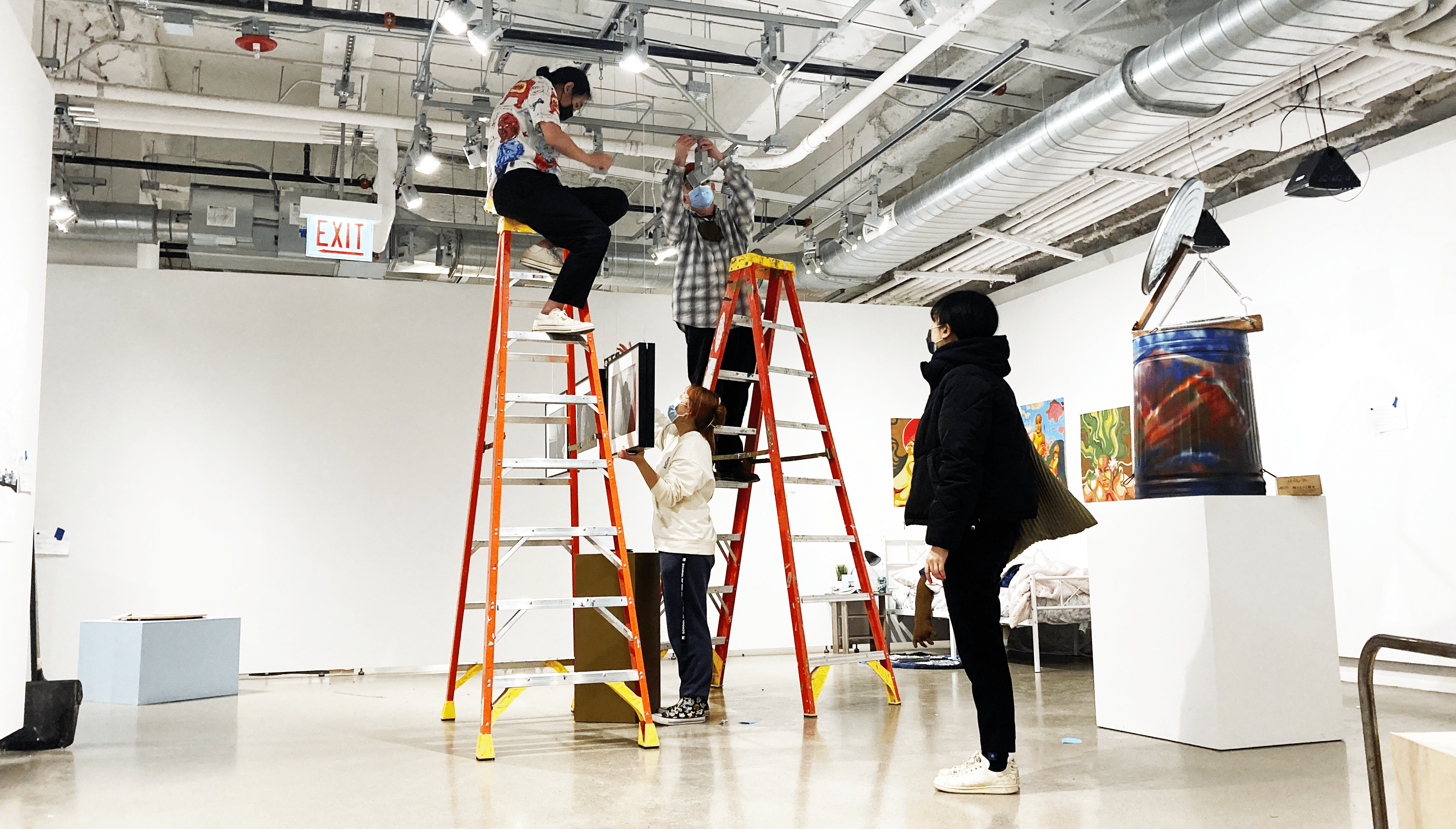 Students and faculty climb ladders to hang things from the ceiling.