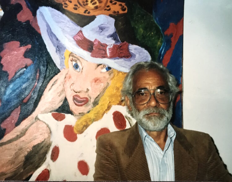 A man sits in front of a caricature-esque painting of a white woman.