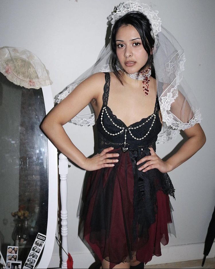 A female model poses in a black dress with a white veil.