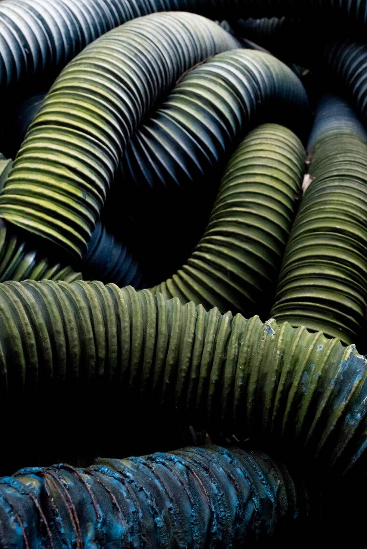 A pile of degrading industrial tubing changes color as the coating deteriorates.