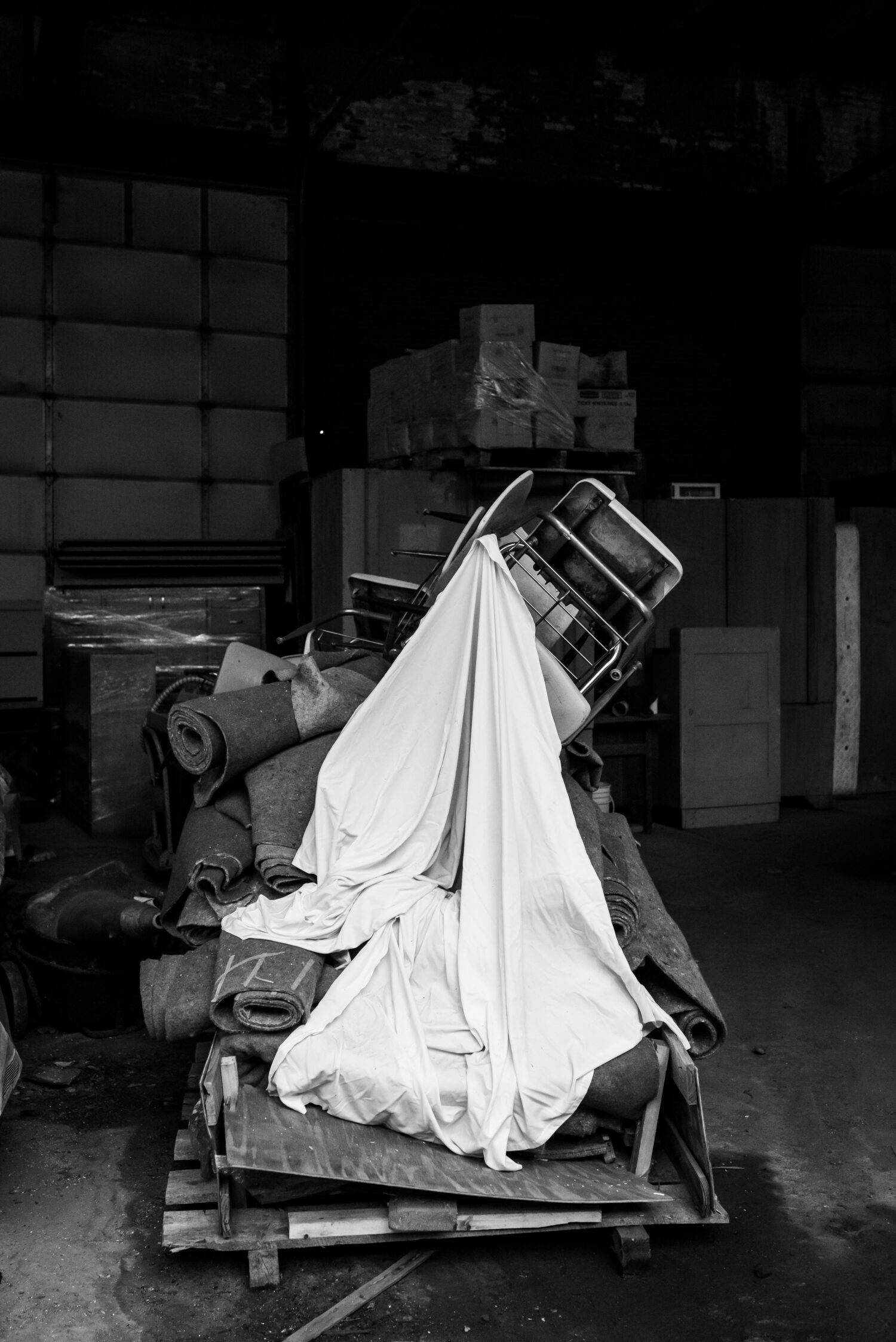 A single white sheets drapes over the various contents of a pallet in the Resource Center’s warehouse. 