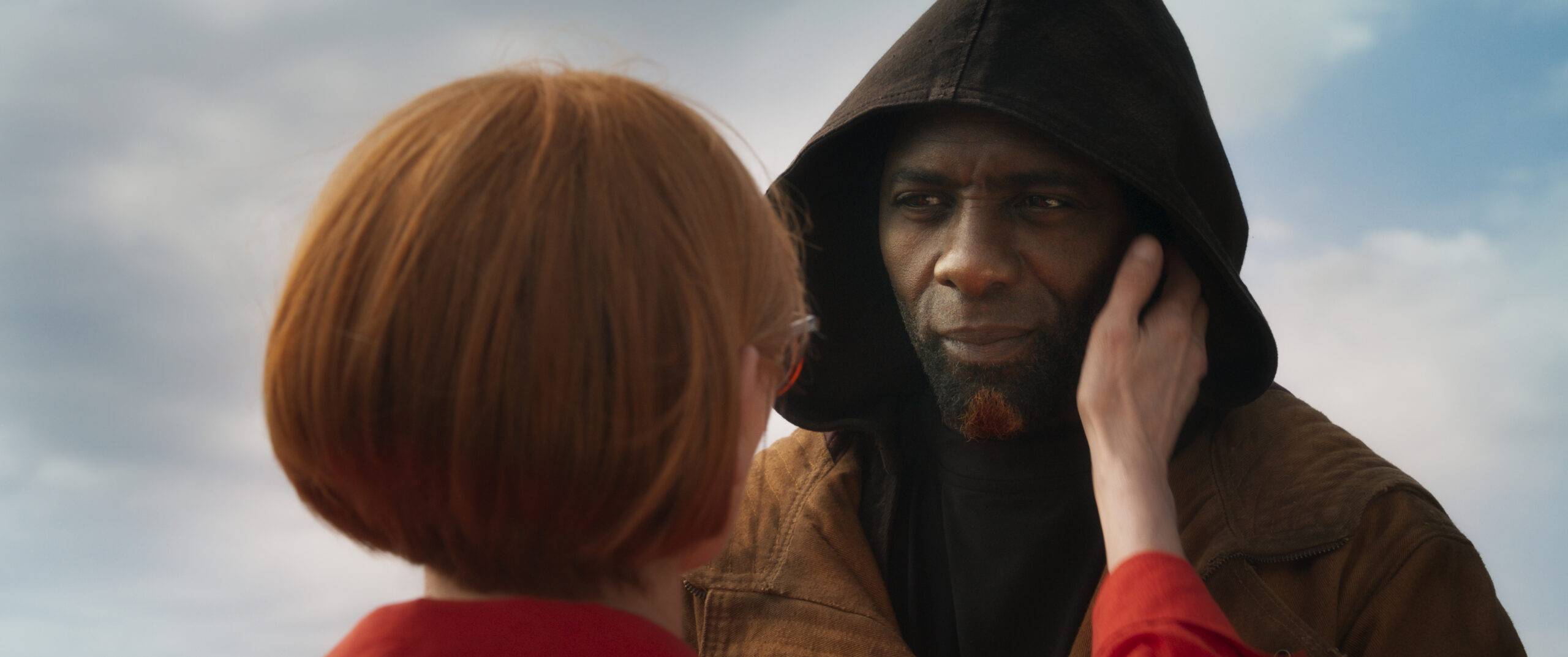 A still from "Three Thousand Years of Longing" showing Tilda Swinton from behind reaching up to cup Idris Elba's face.