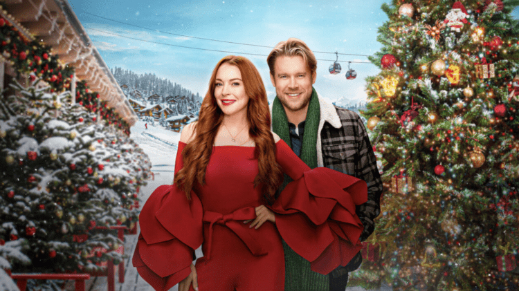 Lindsay Lohan in a sassy pose standing next to Chord Overstreet. Behind them is a Christmas themed sky lodge.