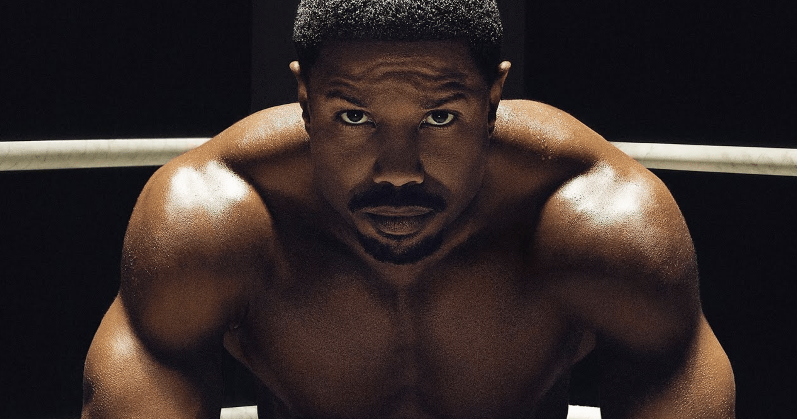 Close up of Michael B. Jordan's face as he sits shirtless in a boxing ring.